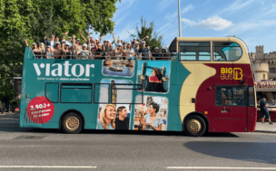 A London Tour Bus wrapped with the Viator campaign creative, with the viator team waving from the top deck.